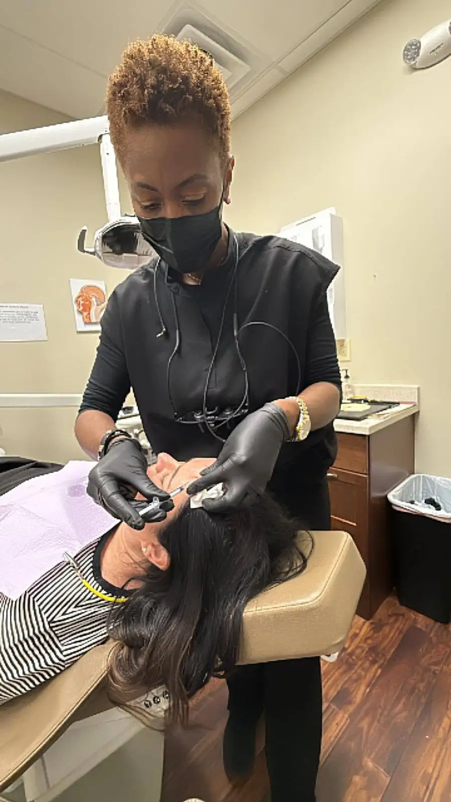 A gloved provider injecting Botox into a relaxed woman's forehead lines