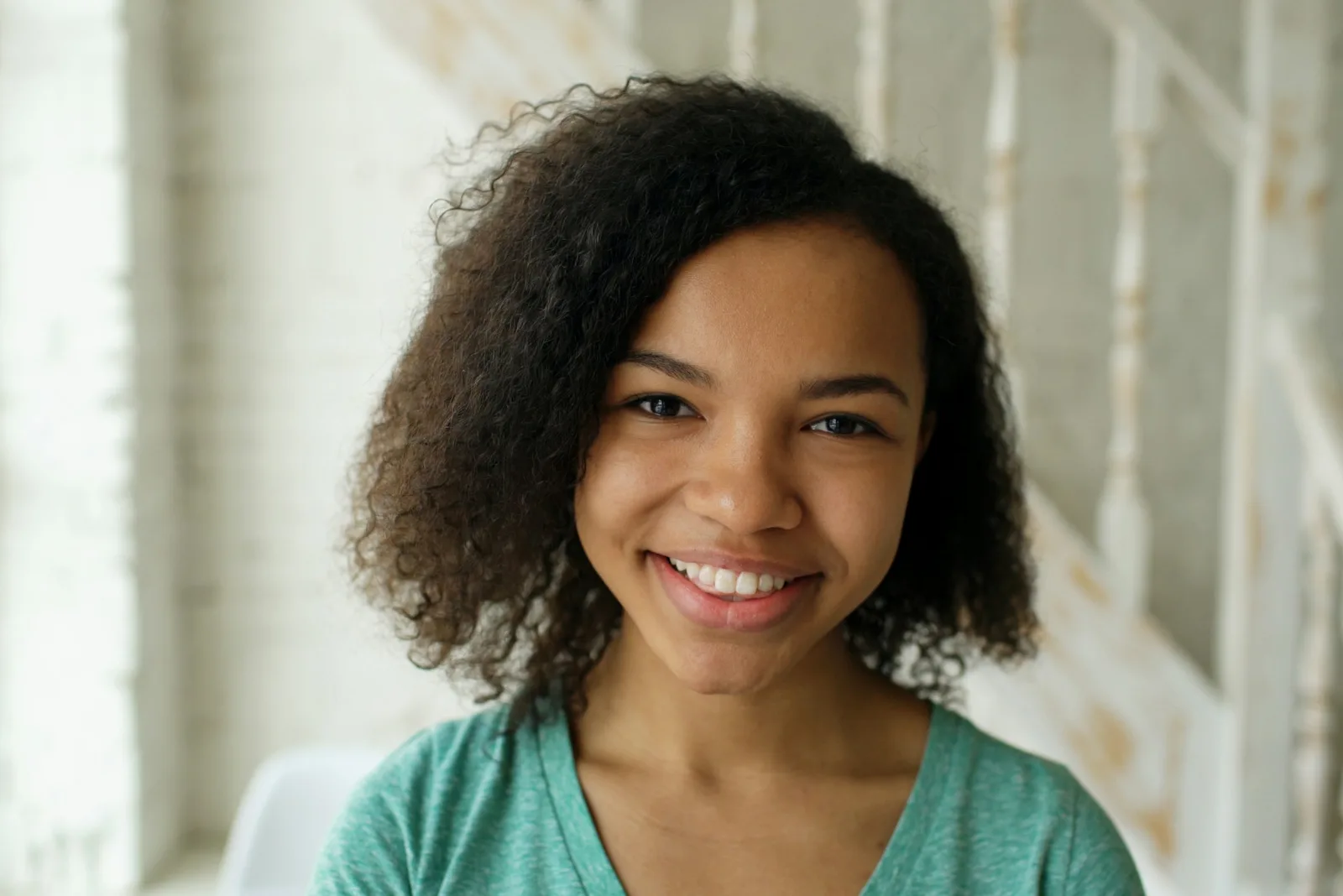 Black woman with curly hair smiling, bright open eyes