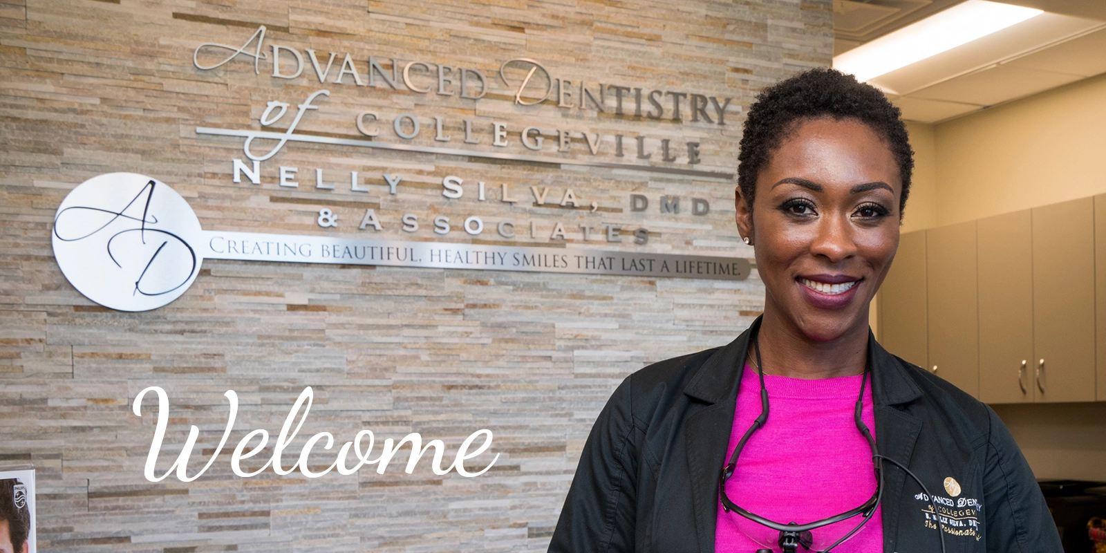 Dr. Nelly Silva smiling at the welcome wall of Advanced Dentistry of Collegeville
